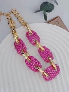 Close-up of vintage chunky gold necklace with sparkly pink rhinestone pig nose links