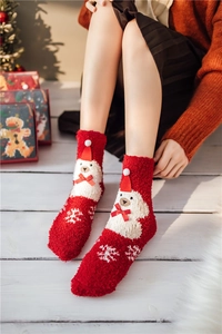 Detail of red coral fleece Christmas socks featuring white bear patterns in a cozy setting