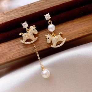 Detailed view of asymmetric gold plated rocking horse earrings with pearls and crystals