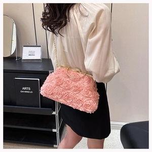 Detailed view of pink fabric rose clutch with elegant gold chain strap on shoulder