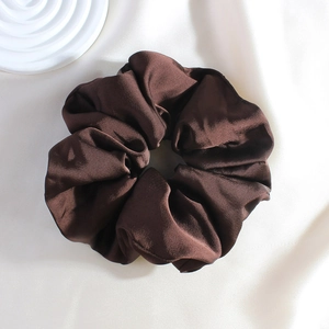 Close-up of a high-quality dark brown satin silk scrunchie on soft silk fabric