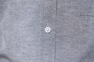 Macro detail of heather grey oxford fabric with white buttons on men's casual shirt