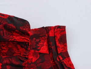 Close-up of red and black jacquard fabric with flutter sleeve texture and stitching