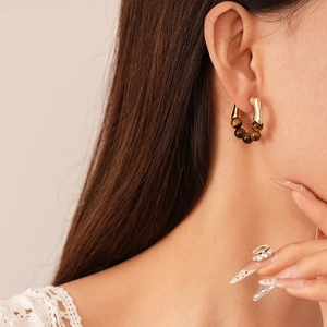 Gros plan de boucles d'oreilles vintage dorées avec perles en pierre œil de tigre