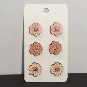 Detailed view of three pairs of wooden pumpkin earrings on a white jewelry card