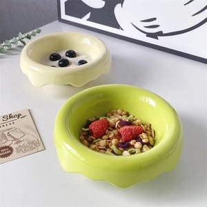 Detail of wavy edge ceramic bowls in pale yellow and grass green with yogurt and berries