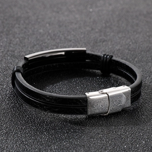 Macro detail of men's double-layer black leather bracelet with silver stainless steel clasp