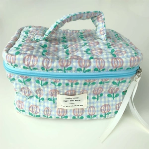 Detail of quilted cotton floral makeup bag with top handle and blue zipper closure