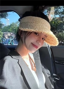 Detail of light khaki straw sun visor with woven texture and frayed edges in a car