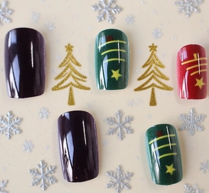 Macro detail of Christmas themed press-on nails with festive patterns and gold glitter