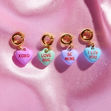 Detail of four colorful heart pendants with romantic engravings on pink silk
