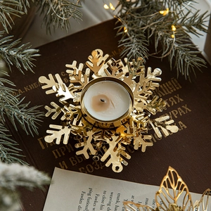 Golden snowflake iron candle holder on vintage books with festive pine and warm lights