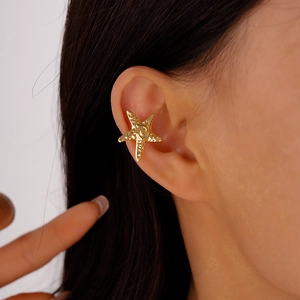Macro shot of a textured golden starfish ear cuff worn on the cartilage area
