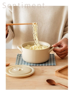 Detail of a cream ceramic noodle bowl featuring vertical striped texture and a vented lid