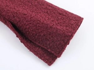 Macro shot of soft burgundy bouclé fabric texture on a slim fit wool-like jacket