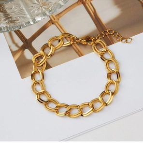 Dettaglio del bracciale a catena dorata con maglie lucide e testurizzate intrecciate