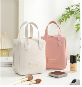 Close-up of portable PU leather shell cosmetic bags in cream and pink with dual zippers