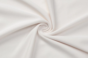 Macro shot of white lace dress fabric showing delicate texture and spiral fold patterns