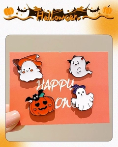 Detailed view of four Halloween enamel pins featuring ghosts and pumpkins on a card