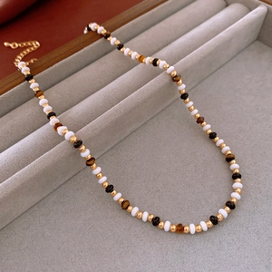 Detail of beaded flower necklace with tiger eye stones and gold accents on jewelry tray