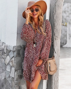 Detail of burgundy V-neck long sleeve dress with white polka dots in outdoor setting