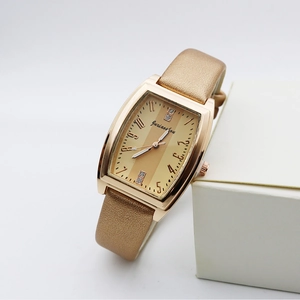 Detailed close-up of golden tonneau women's watch with crystal accents on a white stand