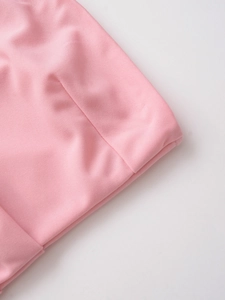 Detailed close-up of pink ruched asymmetric top featuring fine smooth knit fabric texture