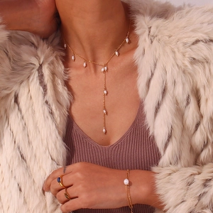Gros plan sur le collier en Y doré et le bracelet assorti avec perles d'eau douce