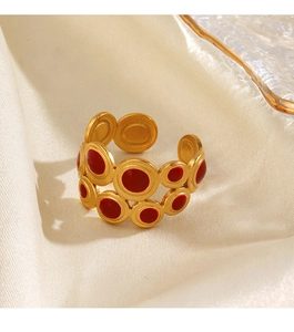 Detail of bohemian gold ring with red enamel dots on premium silk background