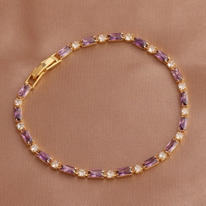 Detail of elegant gold bracelet featuring rectangular purple and white zircons on silk