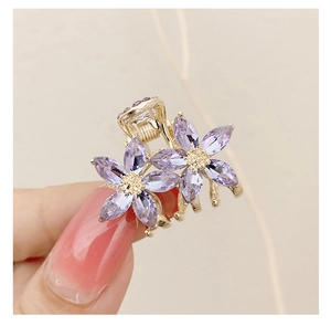 Detail of small gold hair claw clip featuring dual purple crystal flower designs