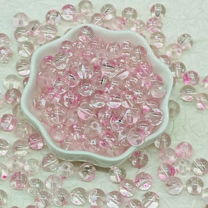 Macro view of transparent floral glass beads with pink spots in a white petal-shaped bowl