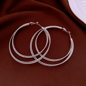 Detailed view of silver multi-layer hoop earrings with textured finish on dark velvet