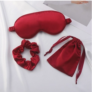 Detailed view of deep red silk sleep mask set including hair scrunchie and drawstring bag