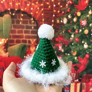 Detail of a handmade green crochet mini Christmas hat for pets with white snowflake sequins