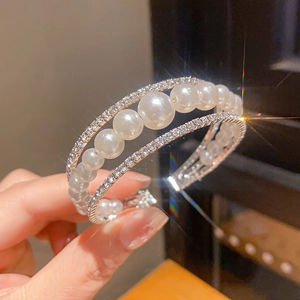 Detailaufnahme eines luxuriösen dreilagigen Perlenarmbands mit funkelnden Strasssteinen