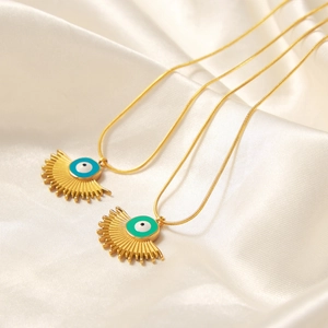 Golden fan-shaped evil eye pendant necklaces with snake chains on silk background