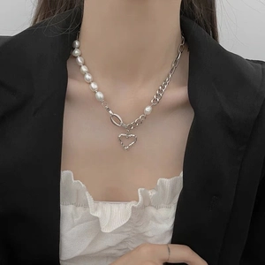 Elegant pearl and silver chain necklace with a hammered heart pendant worn by a model