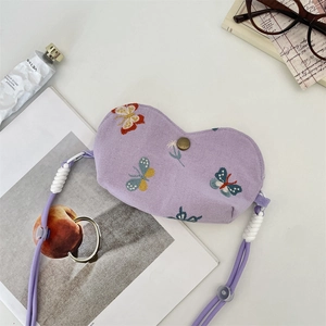 Détail de la pochette cœur lilas avec broderie papillon et cordon de cou réglable