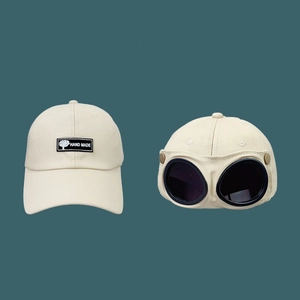 Detail view of cream-colored aviator baseball cap with integrated goggles and embroidery