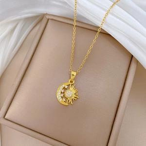 Macro shot of gold sun and moon necklace with sparkling crystals on beige cushion