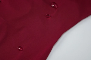Macro shot of water droplets on dark red waterproof dress fabric showing its texture