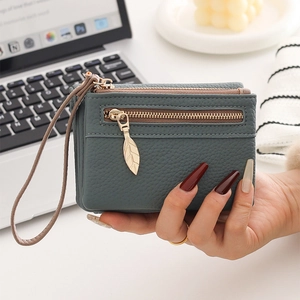 Close-up of greyish-green lychee textured leather mini wallet with metal leaf zipper pull