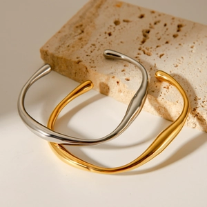 Polished gold and silver irregular wavy stainless steel bracelets on stone base