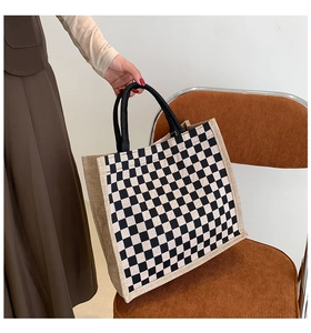 Linen tote bag with black and white checkerboard pattern on corduroy chair