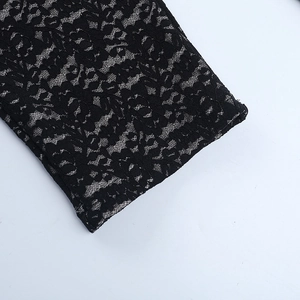 Close-up of intricate black floral lace fabric with beige lining and high knitting density