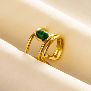 Detail of a vintage hammered gold ring with a green malachite stone on soft fabric