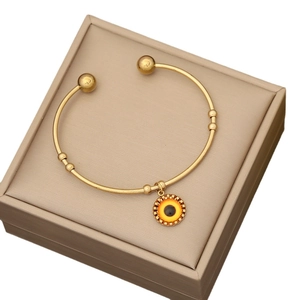 Elegant gold stainless steel open bangle featuring a sun eye charm on a jewelry box