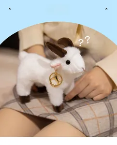 Close-up of white plush goat keychain with brown horns and a golden metal clasp