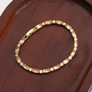Dettaglio del bracciale dorato con pietre di zircone a baguette e rotonde su vassoio